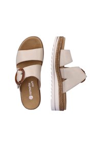 Offene Sandalen aus beigem synthetischem Material, mit zwei breiten Riemen, einer dekorativen braunen runden Schnalle und einer strukturierten weißen Sohle.