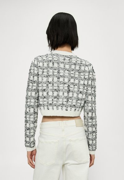 Pull court noir et blanc, présentant un motif checkered texturé, un col rond et des bords-côtes au niveau de l'ourlet et des poignets.