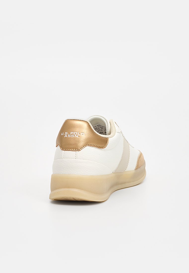Zapatilla blanca con detalles dorados, materiales de cuero liso y malla, forma redondeada, con un cuello acolchado y una suela de goma translúcida.