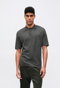 Dunkelgraues kurzärmeliges Poloshirt mit Kragen, ausgestattet mit zwei Knopfverschlüssen und einer glatten Textur. Kombiniert mit dunkelbraunen Cordhosen.