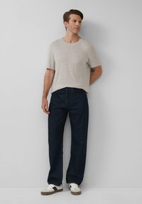 Hellgraues Kurzarm-T-Shirt, lockere marineblaue Jeans und weiße Sneaker mit schwarzen Akzenten. Einfaches, lässiges Outfit mit lockerem Sitz.