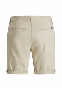 Shorts beige avec revers retroussés, en tissu lisse. Comprend deux poches arrière et un petit détail de marque près de la ceinture.