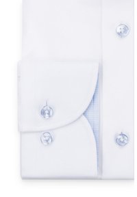 Biała koszula z mankietami, mająca teksturowane wykończenie, niebieską w kratkę podszewkę oraz przezroczyste guziki z logo, ukazująca szczegóły wzoru i fasonu materiału.