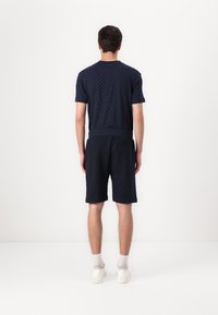 Camiseta de manga corta en color navy y pantalones cortos a juego en tejido texturizado con un patrón de diamantes, que incluye una cinturilla acanalada y bolsillos laterales.