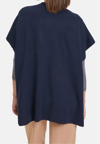 Mörkblå stickad poncho med breda ärmar och rak passform. Har en texturerad tyg och en rundad halsringning, hängande löst över kroppen.