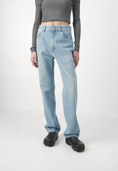 Light blue denim jeans with a relaxed fit, high waist, and five-pocket design. Complemented by a textured gray long-sleeve top and black footwear.