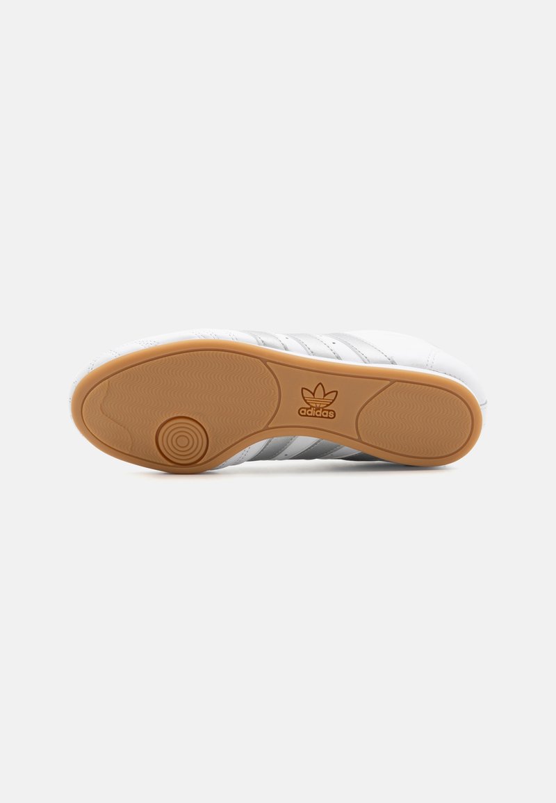 Białe sneakersy z szarymi paskami, teksturowana biała cholewka i podeszwa z gumy z wytłoczonym logo. Płaska podeszwa zaprojektowana dla komfortu.