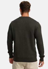 Dunkelgrüner gestrickter Pullover mit Fischgrätenmuster, Rundhalsausschnitt, gerippten Bündchen und Saum; mittlere Textur und taillierte Passform.
