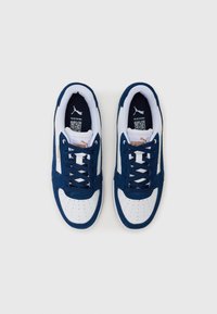 Blue suede sneakers with white leather accents, featuring a perforated toe, white laces, and a logo on the tongue and side panels.