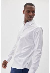 Witte overhemd met lange mouwen en een button-down kraag, gemaakt van een gladde stof, met een subtiele merketiket aan de onderkant.