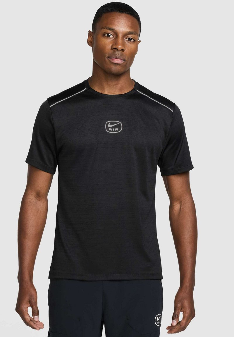 T-shirt nero Nike con maniche corte, colletto a giro e logo riflettente al centro. Tessuto morbido e leggero con una texture sottile.