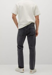 Jeans de mezclilla gris oscuro con corte recto, cinco bolsillos y costuras sutiles; combinados con una camiseta blanca de manga corta y zapatillas.