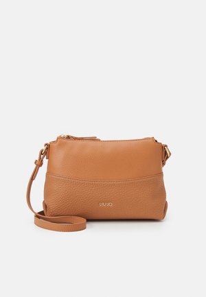 Sac bandoulière en cuir beige avec une finition texturée, fermeture éclair, sangle ajustable et un accent logo en métal sur le devant.