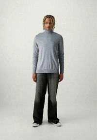 Suéter de gola alta cinza claro com punhos canelados, combinado com jeans largo cinza escuro e sapatilhas pretas. Textura do tecido suave visível.