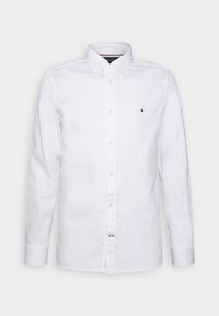 Λευκό πουκάμισο με μακρυά μανίκια και κουμπάκια, φτιαγμένο από βαμβάκι. Διαθέτει κλασικό γιακά και μικρό λογότυπο στην αριστερή περιοχή του στήθους. Ομαλή υφή.