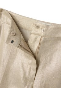 Beige linnenbroek met open ritssluiting, knoop en metalen haaksluiting, waarop het tailleband en de details van de voorkant zichtbaar zijn.