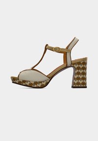 Λευκό και χρυσό πέδιλο με ψηλό τακούνι και σχέδιο με T-λωρίδα, με τακούνι μπλοκ με μοτίβο και υλικά με υφή. Διακοσμητικό αγκράφα σε χρυσό χρώμα.