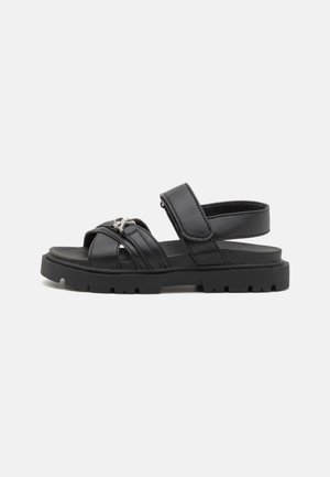 Sorte skinnsandaler med flere stropper, Borrelås-lukking og en tykk gummisåle med et teksturert mønster.