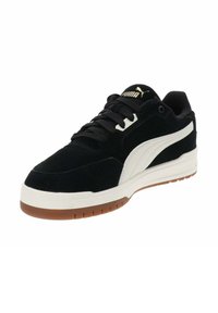 Zapatillas de ante negras con detalles en cuero blanco, que cuentan con cordones planos, una suela de goma y un pequeño logo dorado en la lengüeta.