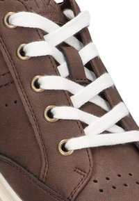 Zapatilla de cuero marrón con cordones blancos, ojales de metal, diseño perforado en los laterales y un acabado texturizado en la parte superior.