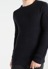 Marinblå ribbad stickad tröja med rund halsringning, långa ärmar och strukturerad tyg; har en smal passform och kontrasterande muddar vid handlederna.