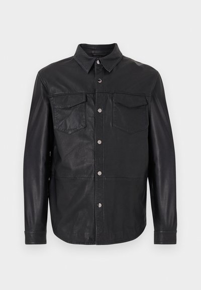 Μαύρο δερμάτινο σακάκι με κουμπιά, γιακά, μακριά μανίκια και δύο τσέπες με καπάκι στο στήθος σε λευκό απλό φόντο.