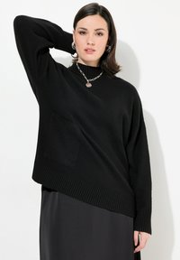 Czarny oversize sweter z dzianiny z ribbowym dołem, wysokim kołnierzem i boczną kieszenią. Posiada długie rękawy i luźny krój. Gładka tekstura.