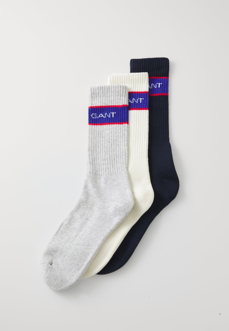 Three pairs of ribbed socks in gray, white, and navy. Each features a contrasting band with "GANT" text and red accent stripes.