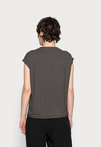 Svart och vit mönstrad kortärmad topp i lätt tyg, med en lös passform och rundad halsringning, med en mjuk yta.