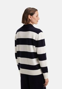 Pull marinière bleu marine et blanc avec un col et des poignets côtelés, affichant une coupe décontractée et une texture en tricot douce, vu de l'arrière.
