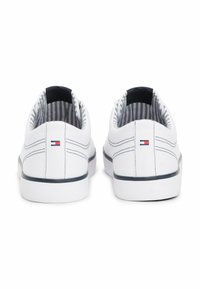 Sneakers bianchi in tela con suola in gomma blu navy, dotati di una fodera interna a righe e un piccolo logo sul retro. Design semplice e a profilo basso.