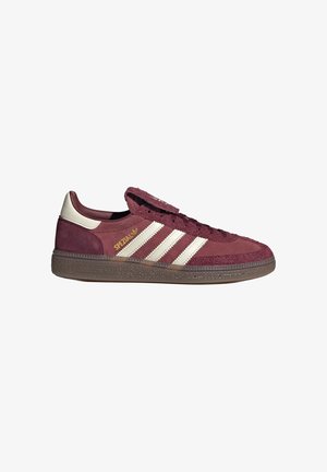 Bordeauxrode suède Adidas Spezial sneaker met witte strepen, gouden "SPEZIAL" tekst en zool van gumrubber, gezien vanaf de buitenzijde.