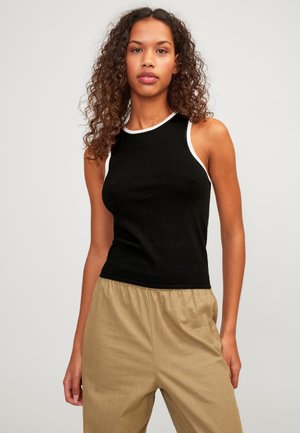 Top negro sin mangas con un cuello y agujeros para los brazos de canalé blanco. Confeccionado en una tela suave, silueta ajustada, combinado con pantalones beige de corte holgado.