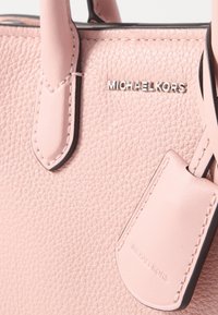 Ružová kožená kabelka s textúrovaným povrchom, striebornými doplnkami a menovkou s embosovaným názvom značky "Michael Kors".