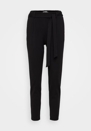 Black tapered trousers made of soft fabric, featuring a waistband with a fabric belt and two front pockets. Smooth texture and minimal design.