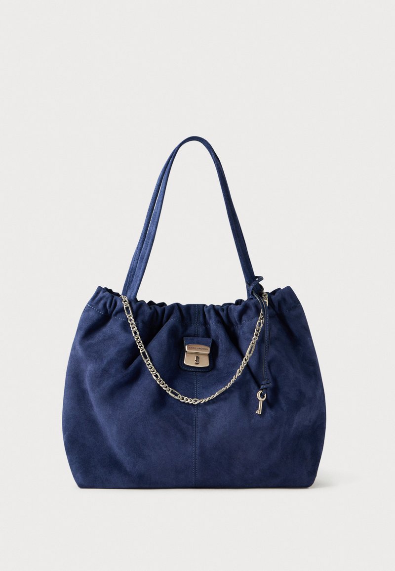 Navy suède handtas met een geplooid ontwerp, dubbele stoffen riemen, een zilverkleurige kettingaccent en een metalen slot met een sleuteldetail.