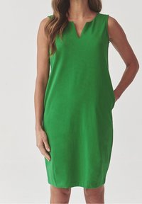 Green sleeveless dress with a V-neckline, made of smooth fabric. Straight cut design with side pockets and a knee-length hem.