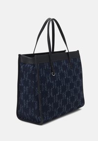 Námořnická taška na rameno s černými koženými doplňky, vyrobená z texturované tkaniny se zdravým vzorem. Dvojité uši a strukturovaný design.