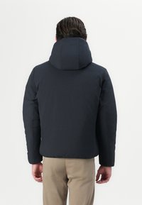 Schwarze Puffjacke mit einer hohen, strukturierten Kapuze, isoliertem Design und glatter Textur. Verfügt über verdeckte Nähte und leicht abgerundete Schultern.