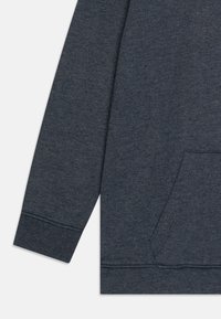 Dunkelgrauer Sweatshirt mit weichem, strukturiertem Stoff, einer Kängurutasche und gerippten Bündchen. Der Ärmel reicht bis zum Handgelenk.