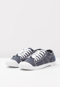 Sneakers in tela di colore blu navy con lacci bianchi, punta in gomma e cuciture bianche a contrasto. Design a taglio basso con una superficie strutturata.