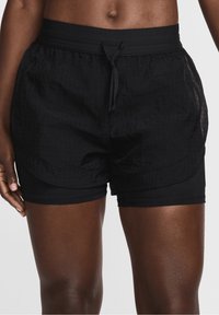 Pantalones cortos deportivos negros con una cintura suave, una capa exterior texturizada y un forro interior, que presentan un cordón para un ajuste ajustable y un diseño en capas.