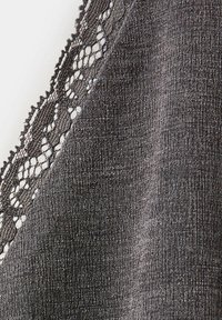 Gros plan sur un tissu gris foncé à tissage texturé avec une bordure en dentelle noire présentant un motif floral le long d’un bord.