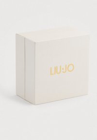 Világos bézs színű, textúrázott, téglalap alakú doboz, arany betűzéssel "LIU·JO" felirattal, középen elhelyezve az elülső oldalon, egy sima fehér háttér előtt.