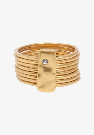 Pierścionek w odcieniu złota z wieloma obrączkami oraz prostokątną złotą płytką z pojedynczym małym, przezroczystym kamieniem szlachetnym na środku.