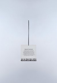 Etiqueta blanca con texto negro y cordón para colgar, que muestra detalles de "Tratamiento Especial" y el logotipo de "NAPAPIJRI" en la parte inferior.
