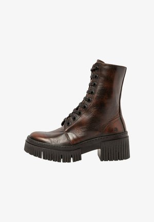 Bottes de combat en cuir marron avec une tête arrondie, un design à lacets et une semelle en caoutchouc épaisse et rainurée. Détail du logo sur le côté visible.