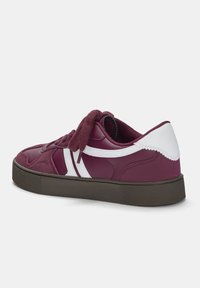 Baskets bordeaux avec des accents blancs, tissu texturé et dessus en cuir, bout rond, semelle en caoutchouc plate, et lacets contrastants.