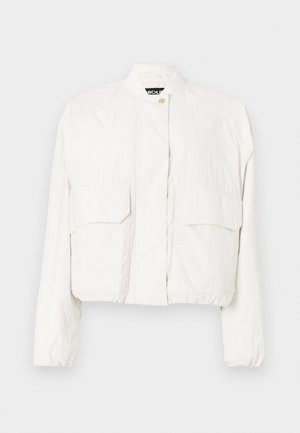 Veste blanche courte en tissu léger, dotée de deux poches avant, d'un col montant et d'une fermeture à pression sur le devant.