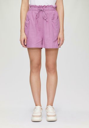 Shorts lilas avec une taille élastique à volants, cordon de serrage et deux poches latérales. Portés avec des baskets blanches et roses.